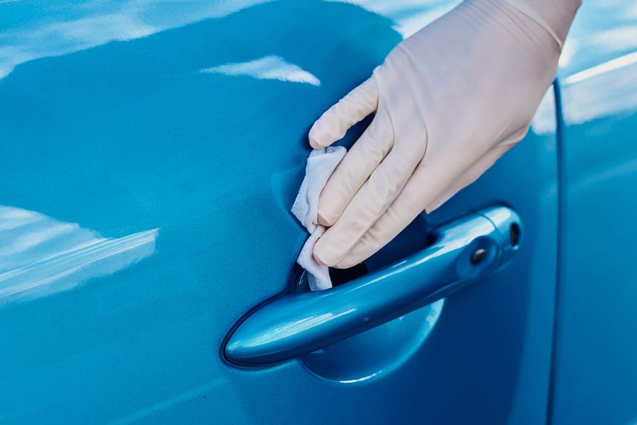 Woman disinfects a car door handle with an antibacterial spray. Car washing